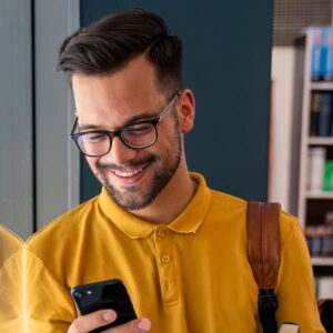 Hombre puertorriqueño con una camisa amarilla mientras mira su teléfono