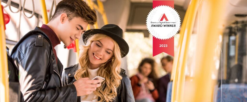 Stylish young man showing a young woman his phone screen while riding a public transit bus