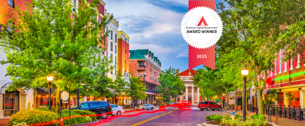 Street level view of downtown Gainesville, FL's buildings and bright lights with the Granicus Award Winner badge overlay